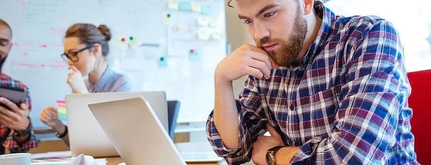 Concentrated bearded young man using laptop while his friends studying together (2) (1) (1)